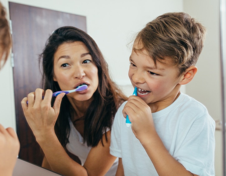 Mother and son brushing teeth in bathroom