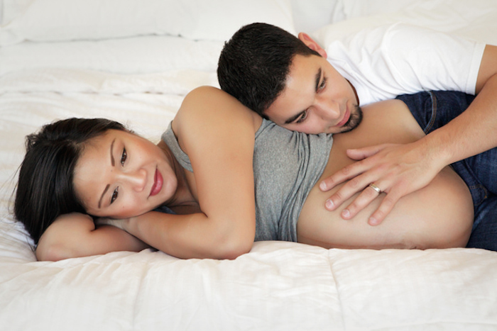 Pregnant woman lying on bed with husband