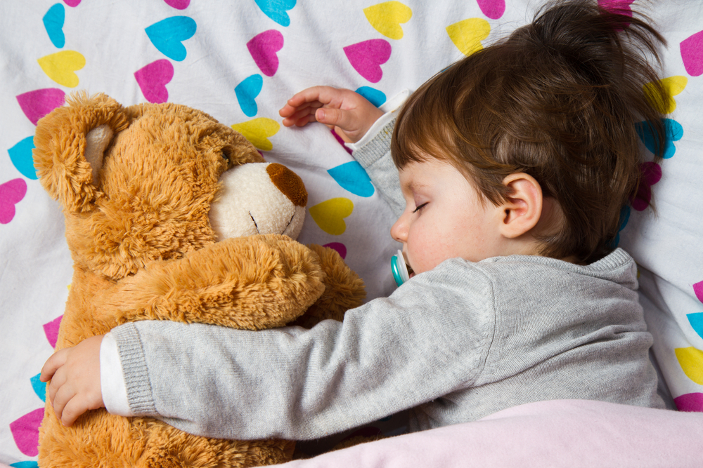 child sleeps with teddy bear
