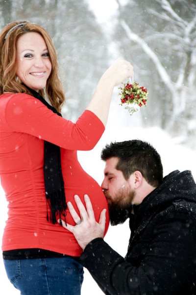 Kissing belly in the snow under mistletoe