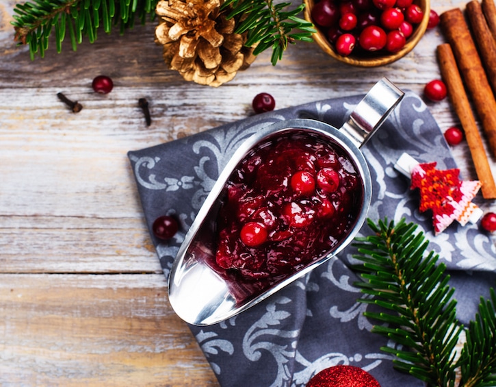 Cranberry sauce with ingredients on wooden table