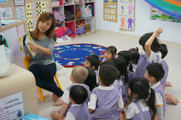 a teacher reads to students at mulberry learning centre preschool in singapore