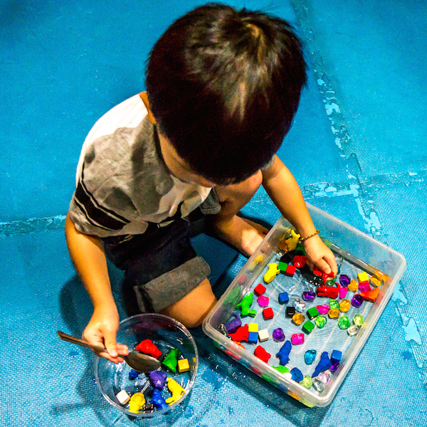 a little boy plays with a tub of water