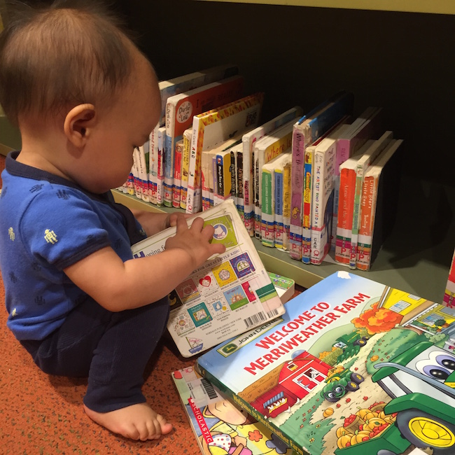 a baby pulls books off a bookshelf at leapfrogs therapy centre