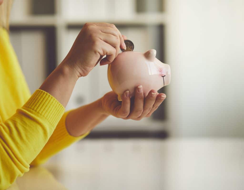 Woman inserts a coin into a piggy bank