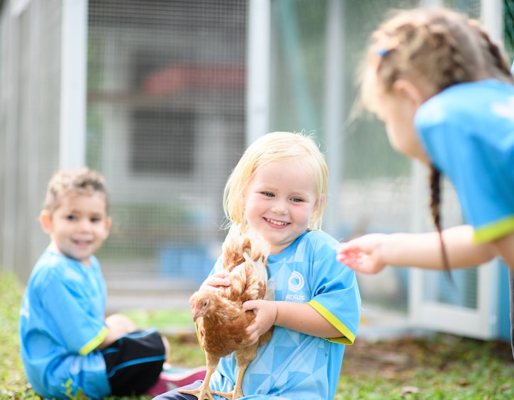 a little girl at nexus international school holds a chicken