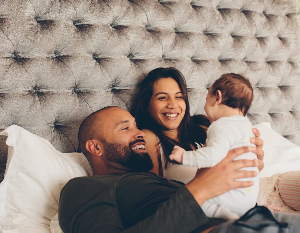 Happy parents playing with their newborn son on bed