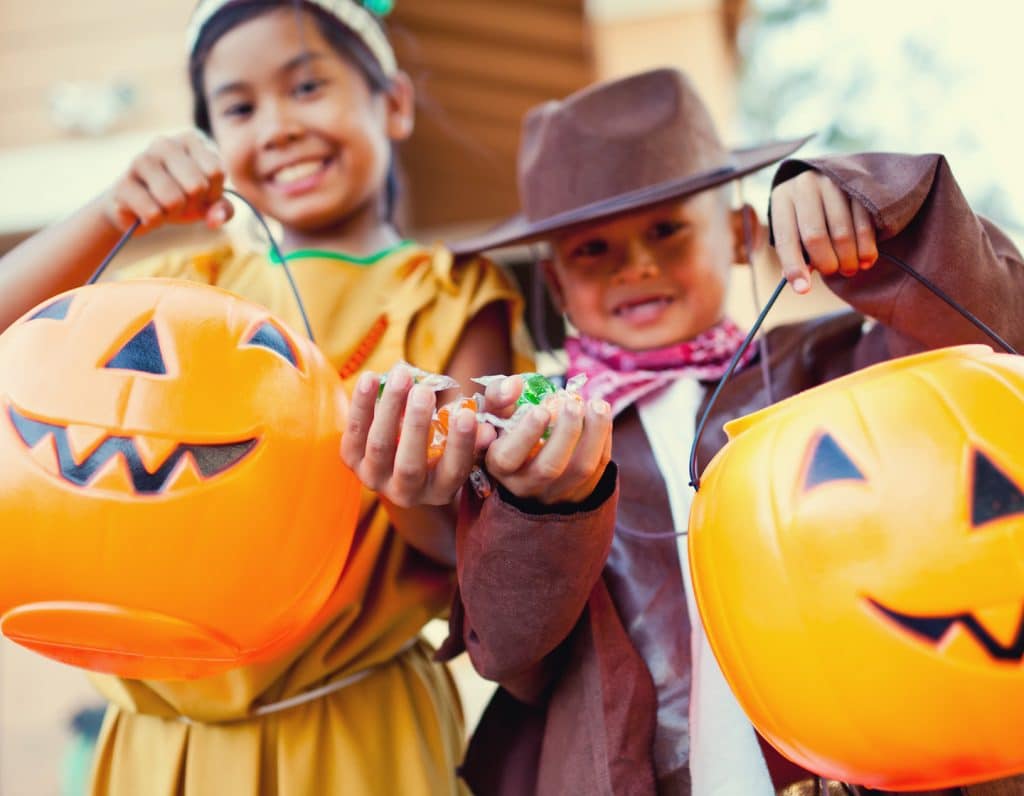 Boy and girl on halloween showing their candy