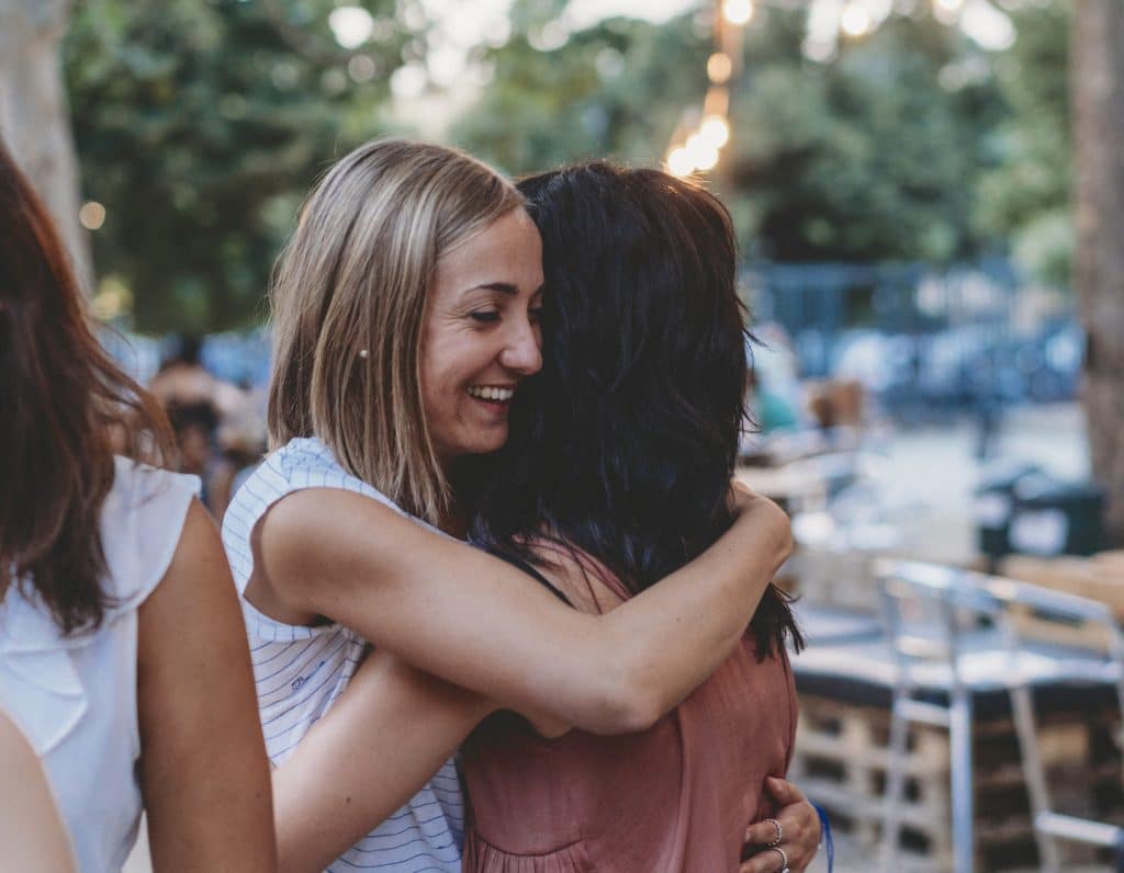 Young Group Of Friends Meeting Up, Hugging And Greeting Each Other