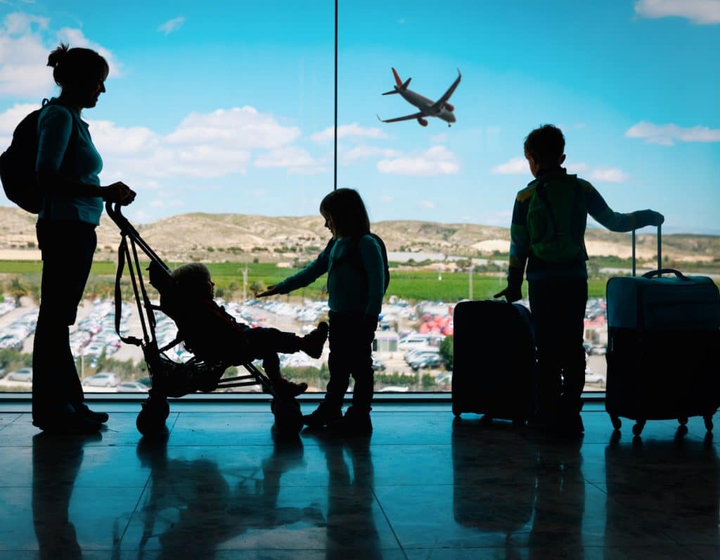 mother with kids and luggage looking at planes in airport