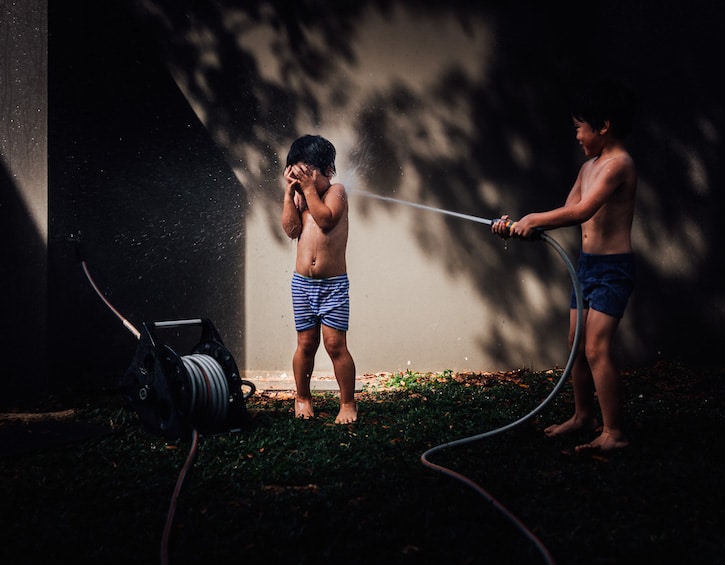 children play with a hose in this image by family photographer kerry cheah