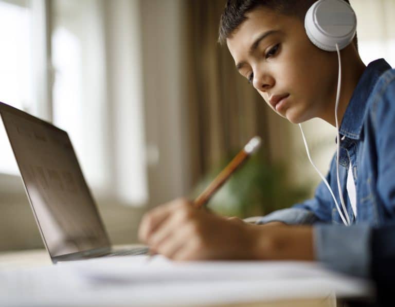 Teenage boy listening to music while doing homework
