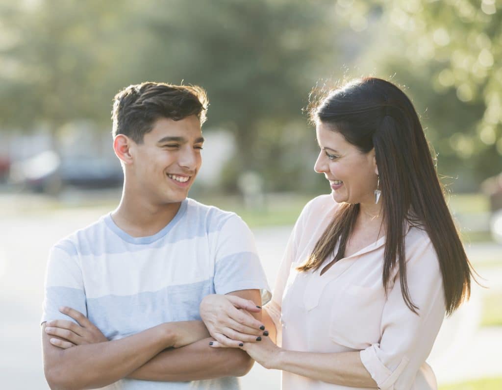 Mother and teenage son standing outdoors