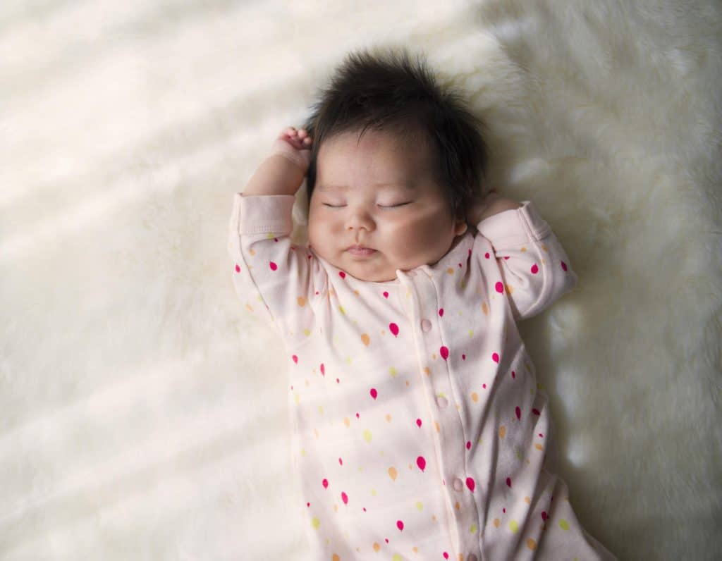 Newborn baby sleeping on a white rug