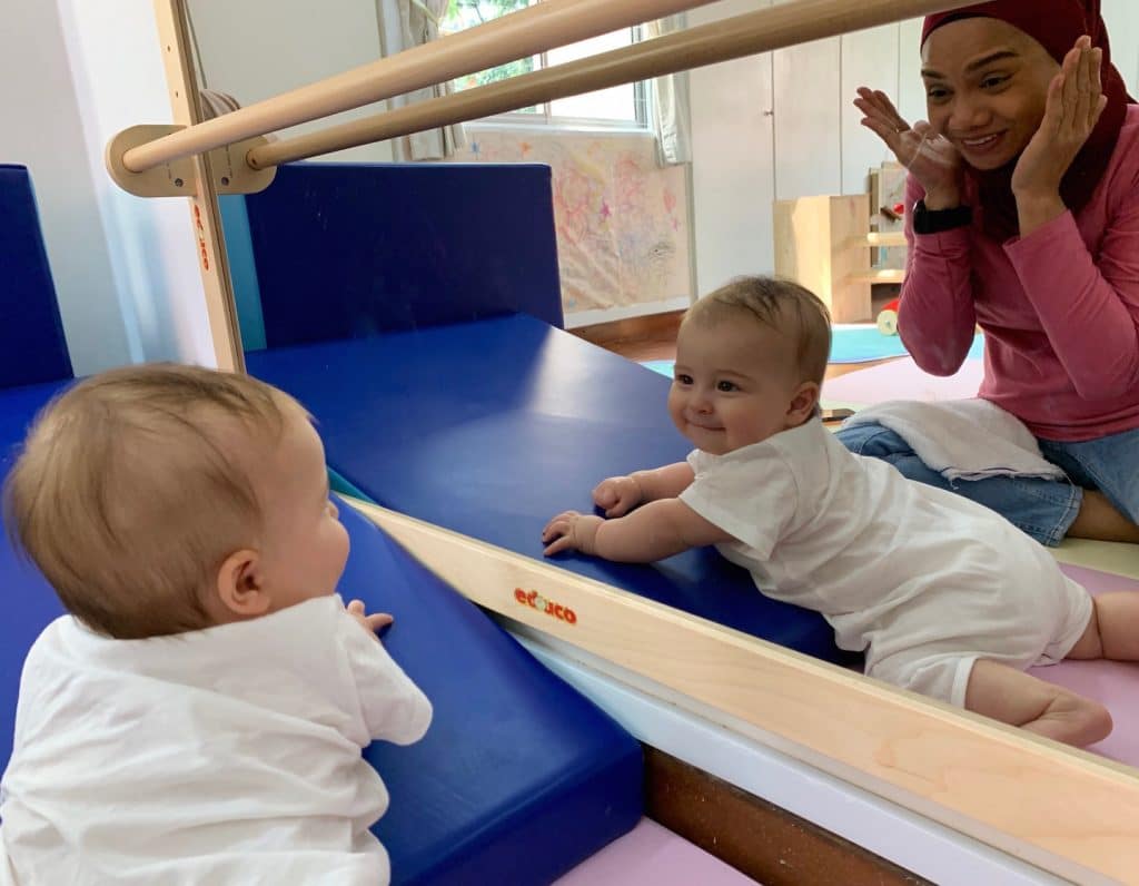 baby plays peekaboo with teacher in the infant programme at house on the hill montessori
