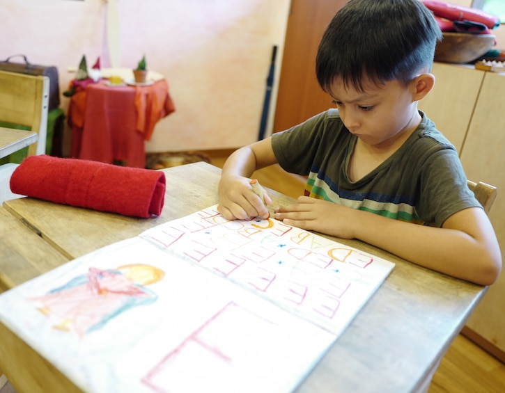 a child at waldorf school singapore writes with crayons