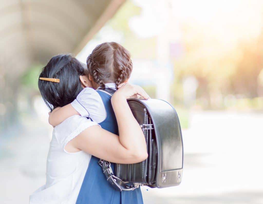mother hugging daughter in uniform student