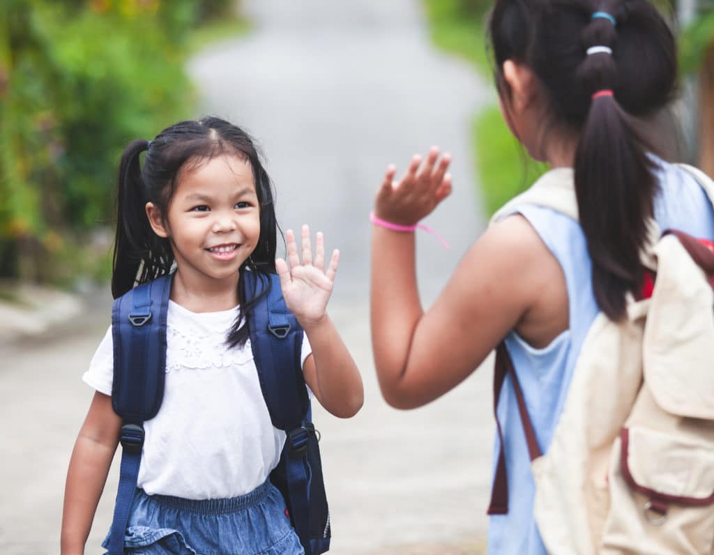 Cute asian child girl with school bag and her elder sister making hi five gesture before go to school