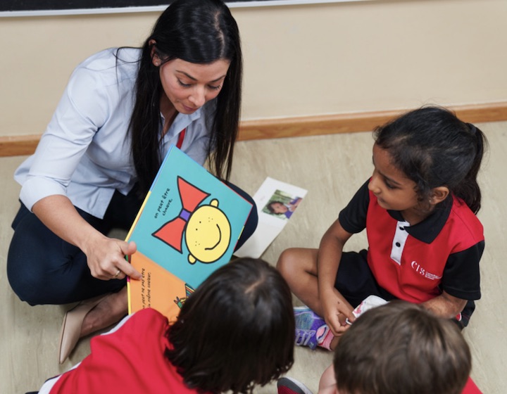 CIS teacher reading a book to students