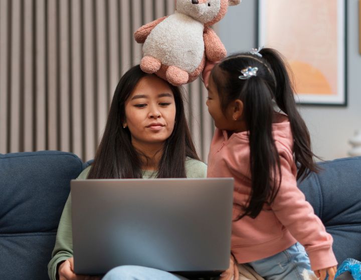 wfh mum problems singapore - mother working on laptop while child tries to get attention with toy